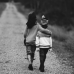 Dos niños pequeños caminando de espaldas por un camino