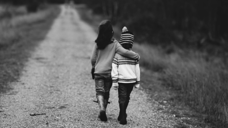 Dos niños pequeños caminando de espaldas por un camino