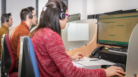 Varias personas sentadas en una sillas frente a un ordenador trabajando en el Call-Center de DFA