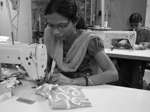 Mujer india cosiendo en un taller de costura