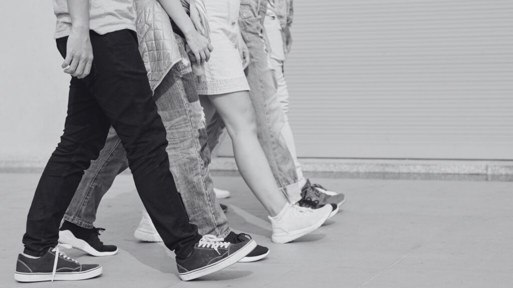 Cuatro personas de tronco para abajo caminando juntas en la misma direccion