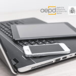 ortátil, tablet y smartphone colocados juntos sobre una superficie, con los logotipos de la AEPD y el Pacto Digital para la Protección de las Personas en la parte superior, simbolizando tecnología y compromiso con la protección de datos.
