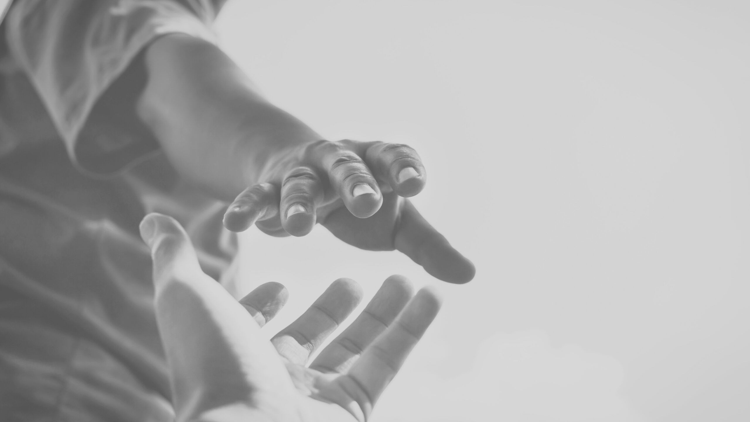 Dos manos alcanzándose, con una en movimiento hacia la otra en un fondo suave y desenfocado