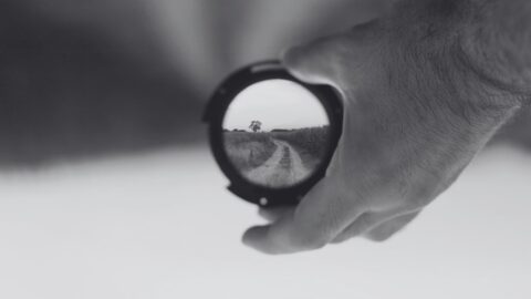 Imagen de una mano sujetando un objetivo de cámara de fotos enseñando el camino