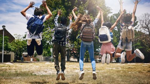 Niños saliendo del cole dando saltos de alegria antes de comenzar las vacaciones